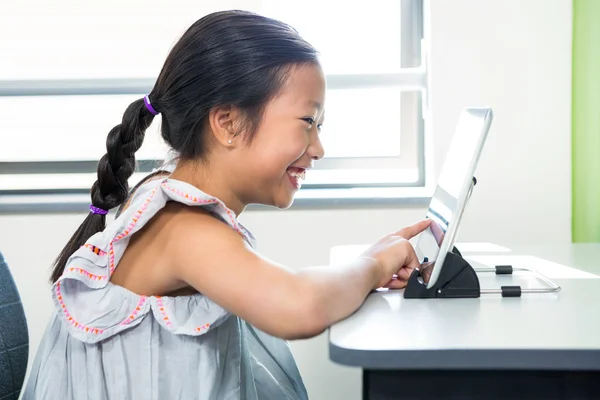 Sonriente chica usando el ordenador portátil en el aula —  Fotos de Stock