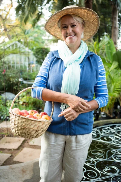 Mujer de pie con manzanas en el jardín —  Fotos de Stock