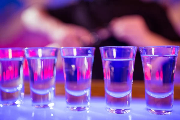 Shot glasses on illuminated bar counter — Stock Photo, Image