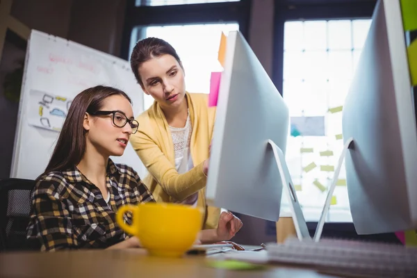 Female colleagues discussing over computer — Stock Photo, Image