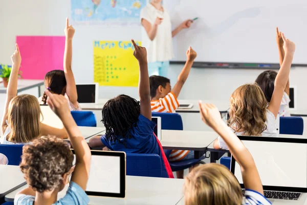 Leraar aanwijsapparaat studenten met opgeheven handen — Stockfoto