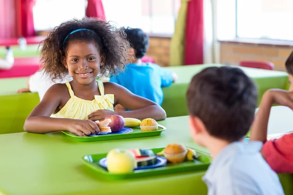 Ragazza sorridente con compagni di classe che mangiano — Foto Stock