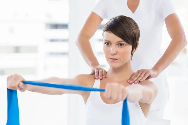 Vrouw met trainer holding weerstand band — Stockfoto