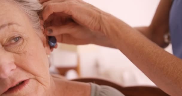 Врач вставляет слуховой аппарат в ухо пожилых женщин — стоковое видео