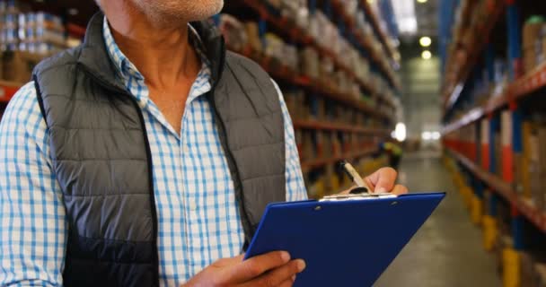 Trabajador de almacén escribiendo en portapapeles — Vídeos de Stock