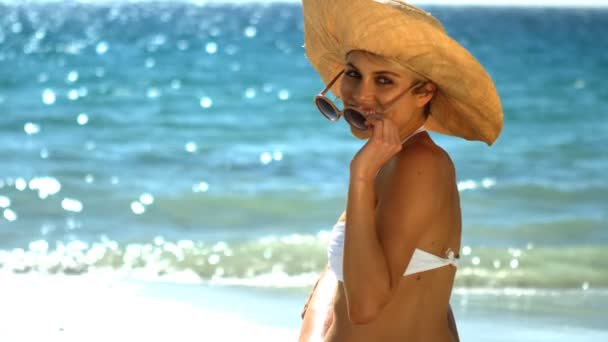 Junge Frau im Bikini sitzt am Strand — Stockvideo