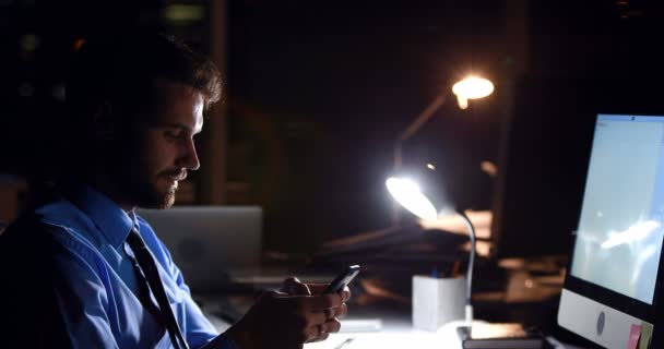 Businessman using smartphone and computer at night — Stock Video