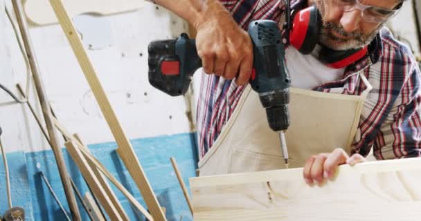 Geconcentreerd timmerman spijkeren een plank hout — Stockvideo