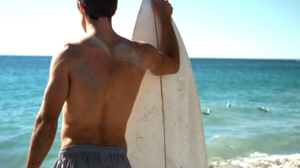 Man bedrijf surfplank op strand — Stockvideo