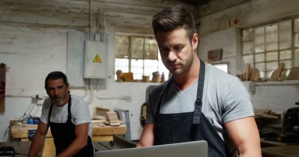 Carpinteros mirando el ordenador portátil mientras trabajan — Vídeos de Stock