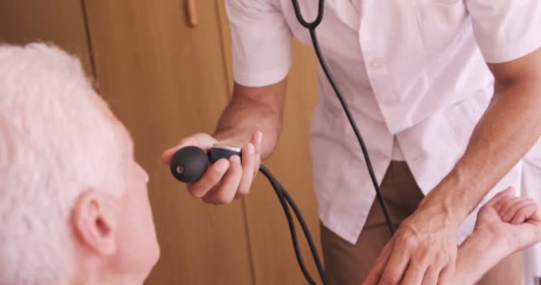 Male doctor checking blood pressure of senior man — Stock Video