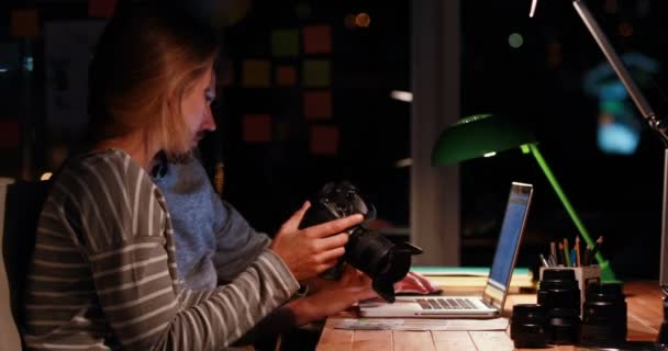 Коллеги используют ноутбук и камеру ночью — стоковое видео