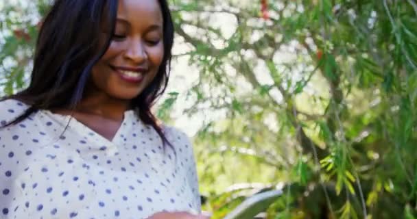 Woman is using smartphone in the garden — Stock Video