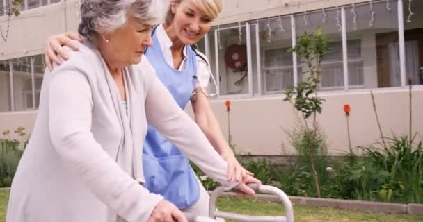 Медсестра помогает пожилой женщине ходить — стоковое видео