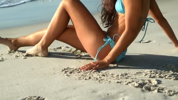 Ung kvinna sitter på stranden — Stockvideo