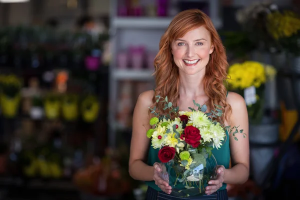 Fiorista femminile che tiene vaso di fiori al negozio di fiori — Foto Stock