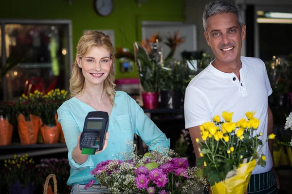 Florista sorrindo mostrando terminal de cartão de crédito — Fotografia de Stock