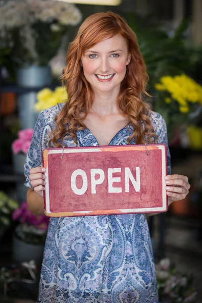 Leende florister håller open sign plakatet i blomsteraffär — Stockfoto