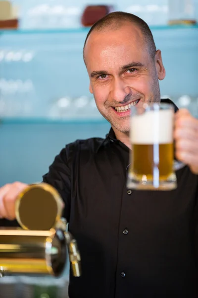 Bar tender in possesso di bicchiere di birra — Foto Stock