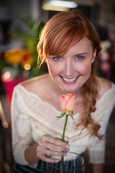 Porträtt av kvinnliga florist att lukta en rosa blomma — Stockfoto