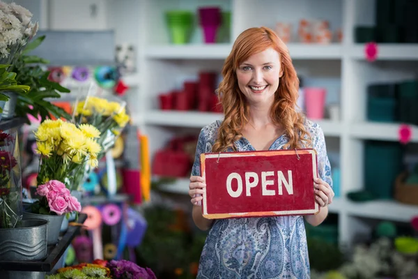 Leende florister håller open sign plakatet i blomsteraffär — Stockfoto