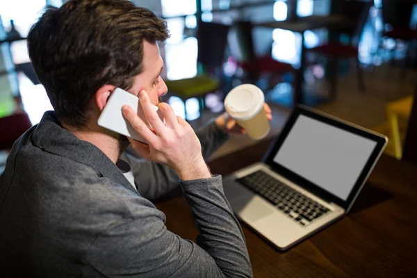 Man met wegwerp koffiekopje tijdens het gesprek op mobiele telefoon — Stockfoto