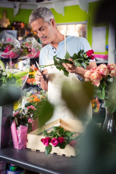 Male florist trimming stems of flowers — Stock Photo, Image