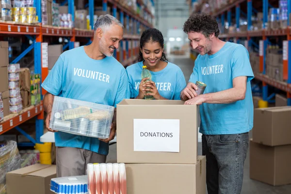 Szczęśliwy, że wolontariusze są patrząc wewnątrz pudełka darowizny — Zdjęcie stockowe