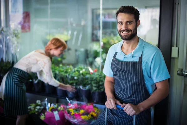 Fleuriste masculin debout tandis que la fleuriste féminine travaillant dans le backgr — Photo