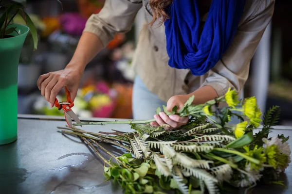 Blumenhändlerin trimmt Blütenstiel — Stockfoto