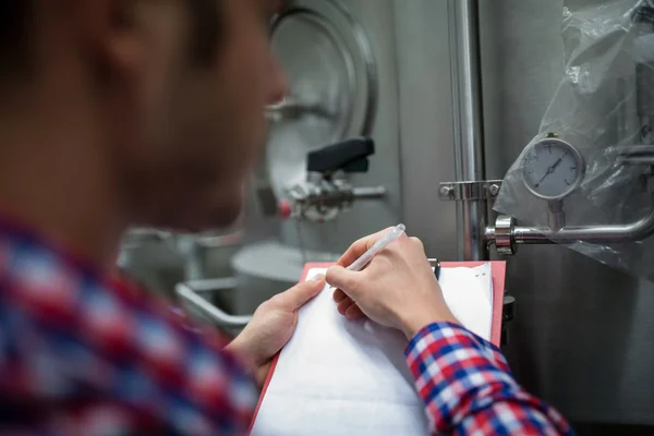 Maintenance worker writing on clipboard — Stock Photo, Image