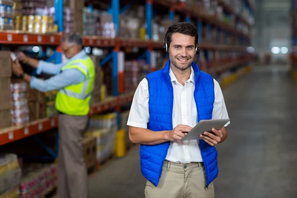 Stehender Arbeiter lächelt in die Kamera, während er ein digitales Tablet in der Hand hält — Stockfoto