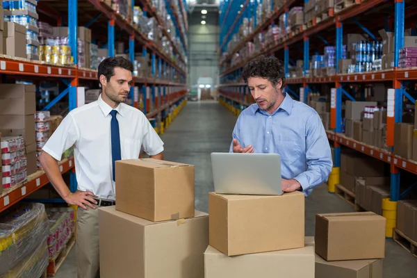 Los gerentes que trabajan con un ordenador portátil poner en una caja de cartón — Foto de Stock