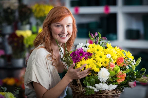 Heureux fleuriste femelle tenant panier de fleurs — Photo