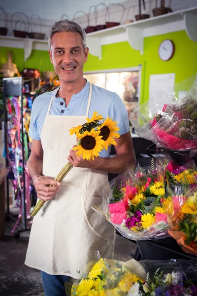 Male florist holding bunch of yellow sunflower — Stock Photo, Image