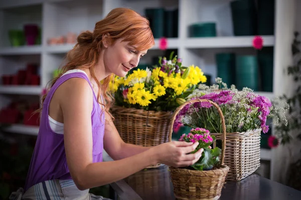 Female florist preparing basket of flowers — Stock Photo, Image