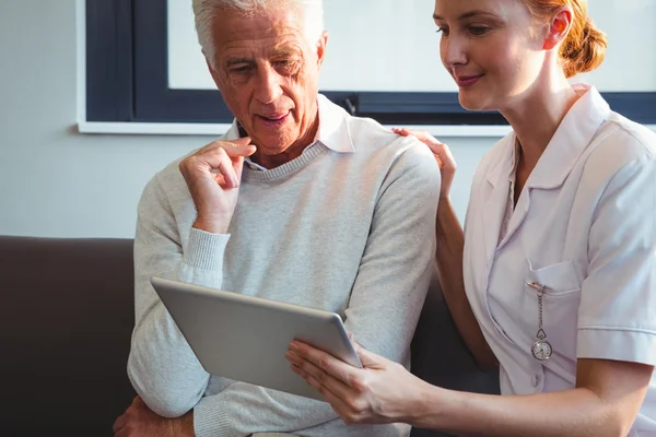 Enfermeira e homem idoso usando um tablet digital — Fotografia de Stock