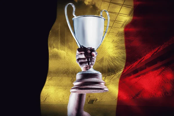ベルギーの旗に対してトロフィーを持っている手 — ストック写真