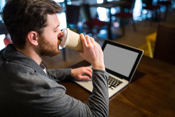 Man having coffee while using laptop — Stock Photo, Image