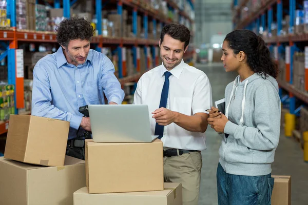 Equipe de trabalhadores procurando um laptop colocar em uma caixa de papelão — Fotografia de Stock