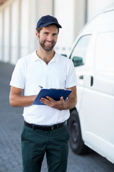 Portrait of delivery man is holding a clipboard and smiling — Stock Photo, Image