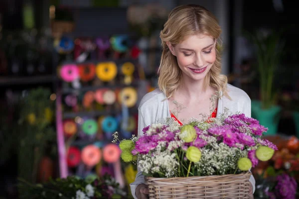 Feliz florista femenina sosteniendo cesta de flores —  Fotos de Stock