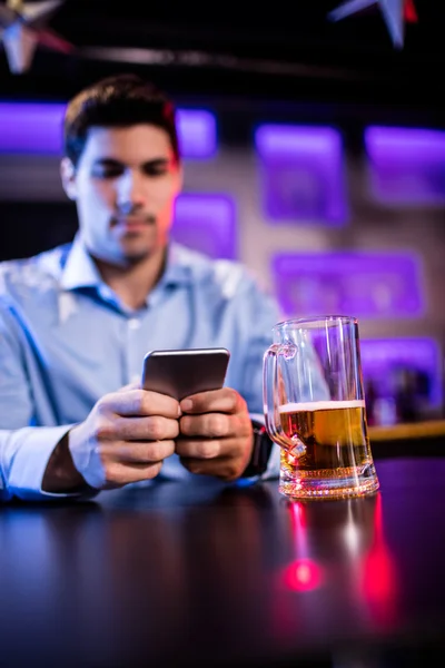 Homme utilisant un téléphone portable au comptoir du bar — Photo