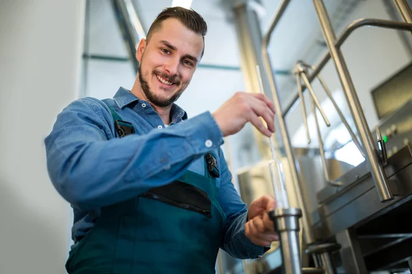 Brewer checking beer with hydrometer — Stock Photo, Image