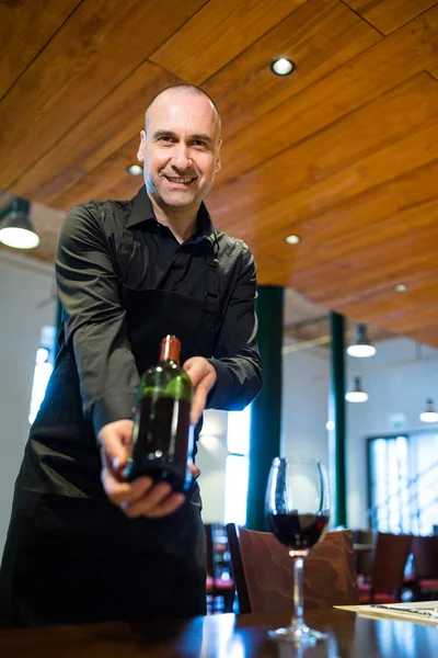 Cameriere con in mano una bottiglia di vino rosso — Foto Stock