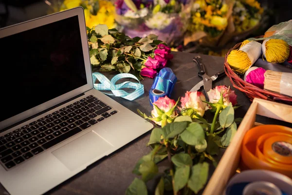 Computadora portátil y floristería sobre la mesa — Foto de Stock