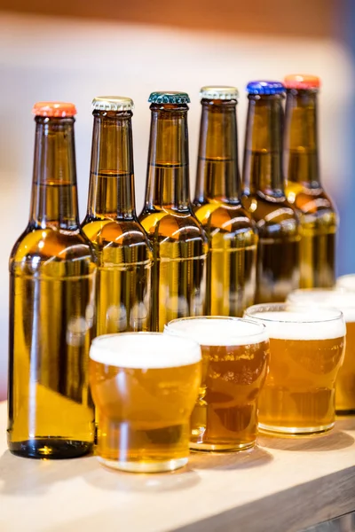 Copos de cerveja arranjados e garrafas no balcão do bar — Fotografia de Stock