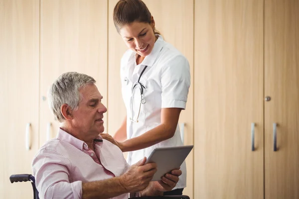 Senior met behulp van een tablet in een rolstoel — Stockfoto