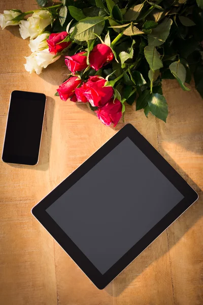 Massa rosor med smartphone och digital tablet på trä — Stockfoto