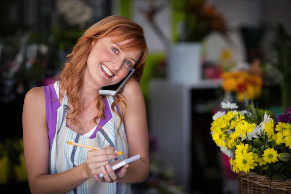 携帯電話で注文を取って女性の花屋 — ストック写真